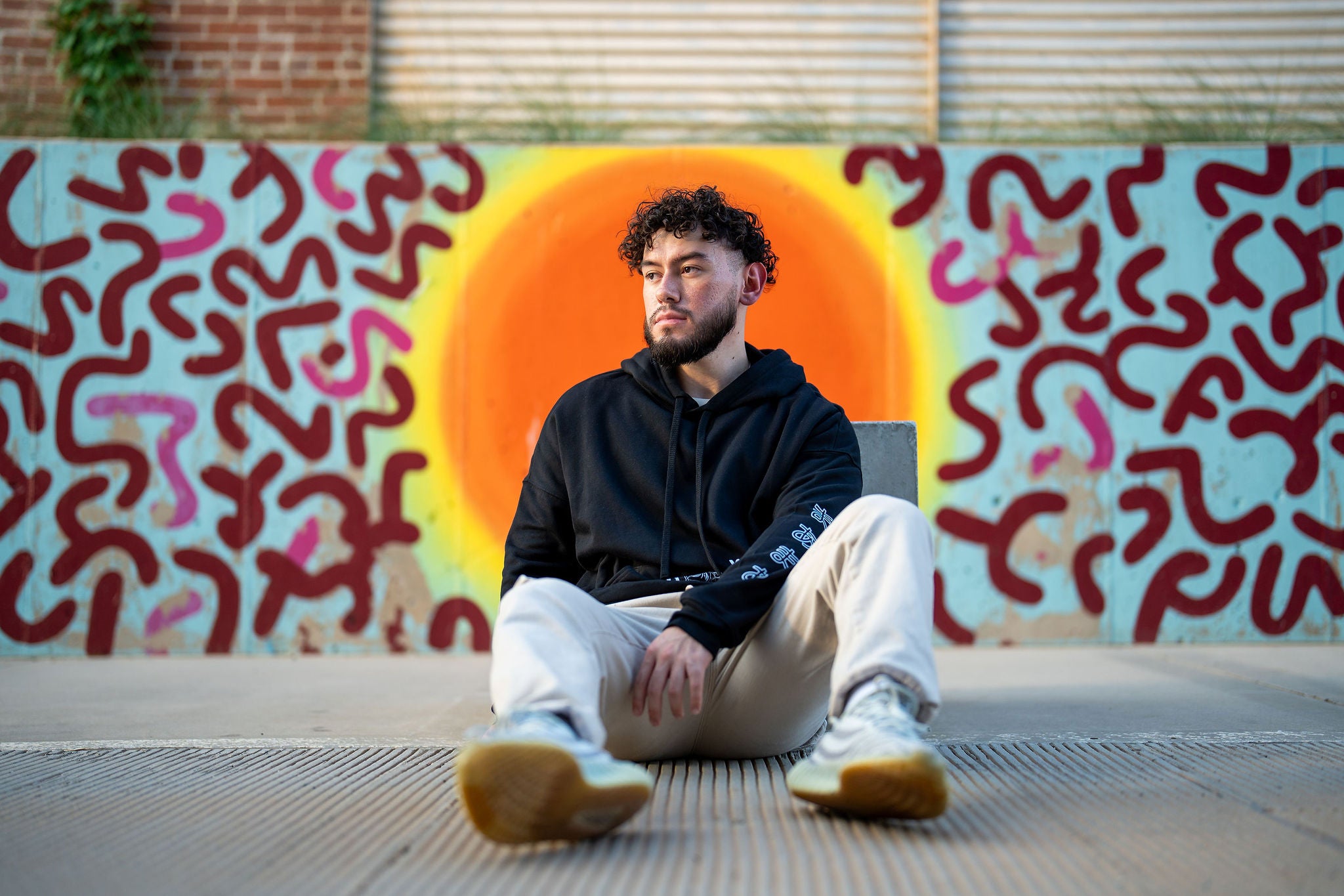 Guy sitting wearing black streetwear hoodie